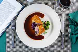A plated Paysanne dish with sauce and vegetables